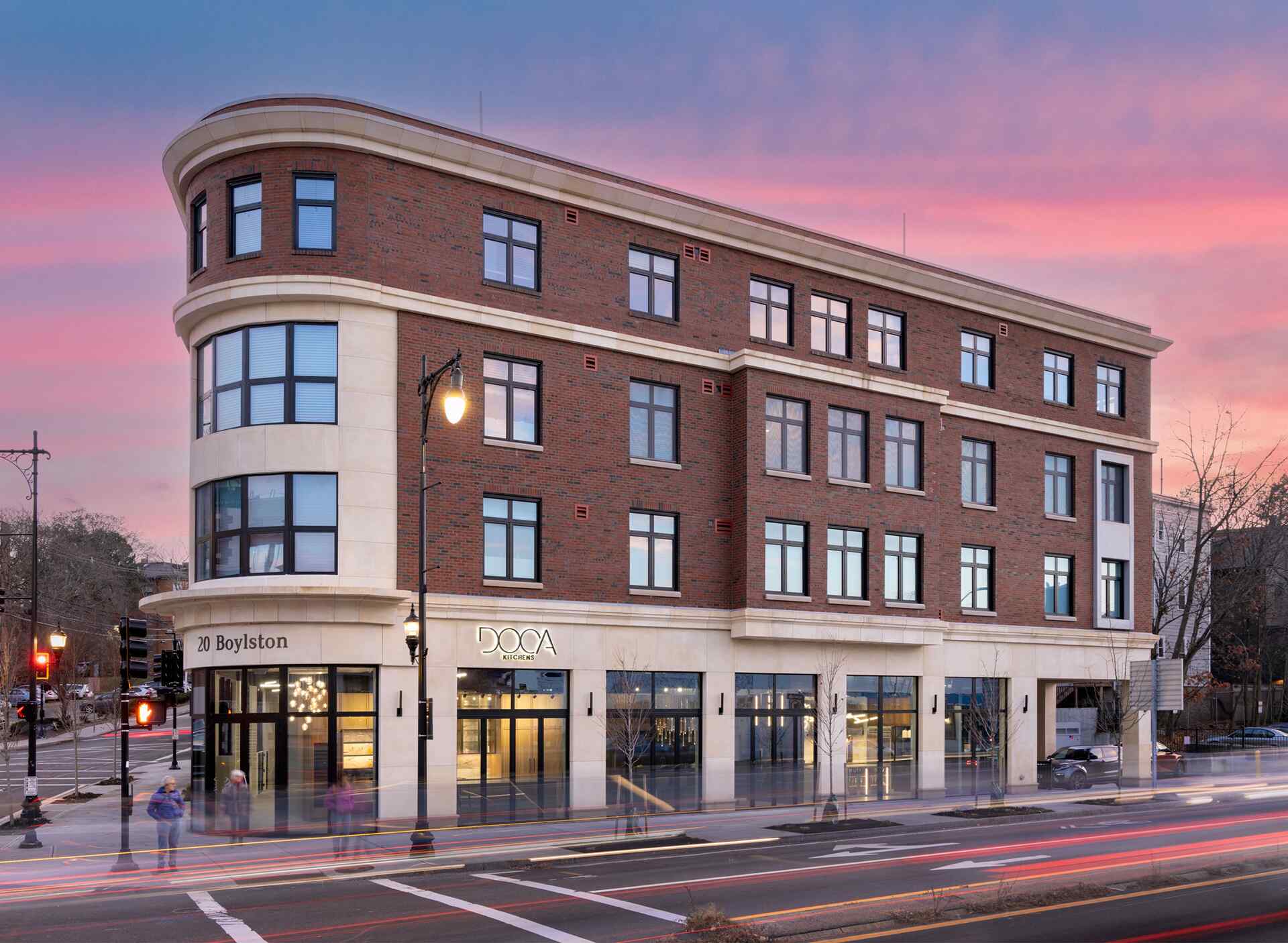 Exterior of a multi-story brick building at dusk with a "DOCA Kitchens" storefront.