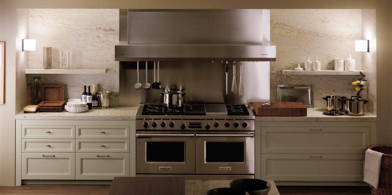 An opulent kitchen with cream cabinetry, marble countertops, chandeliers, and a decorative patterned floor, with a warm and inviting atmosphere.