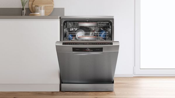 Bosch stainless steel dishwasher with an open door displaying clean dishes neatly arranged on adjustable racks.