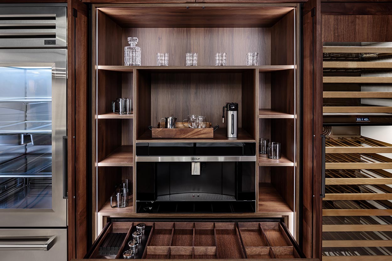 This luxurious **Boston kitchen cabinet** setup features custom wood shelving, a built-in coffee machine, and organized glassware storage, offering an elegant and functional solution for **kitchen cabinetry options in Boston** homes.