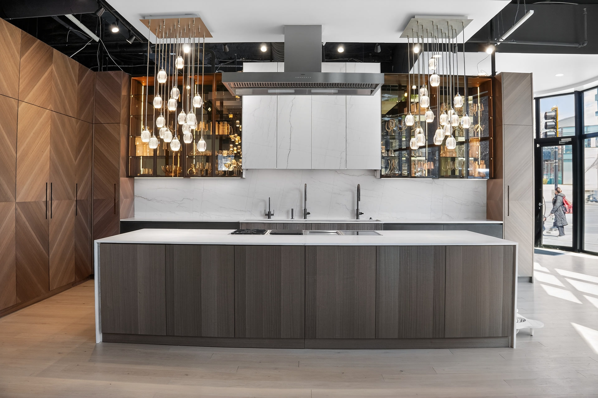 Renovated DOCA Boston showroom kitchen with walnut cabinetry, illuminated glass displays and a stone island
