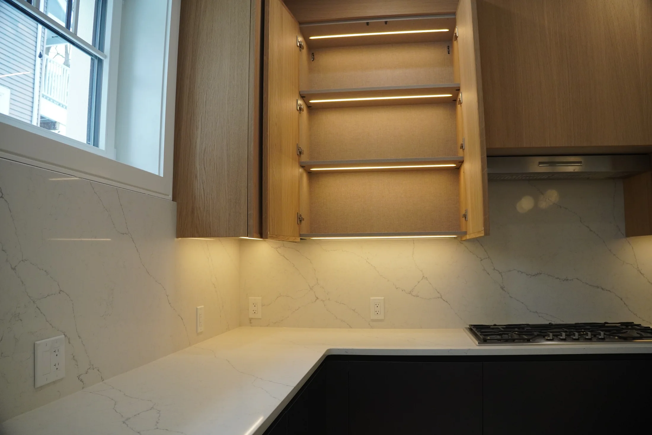 Illuminated storage integrated into warm wood cabinetry