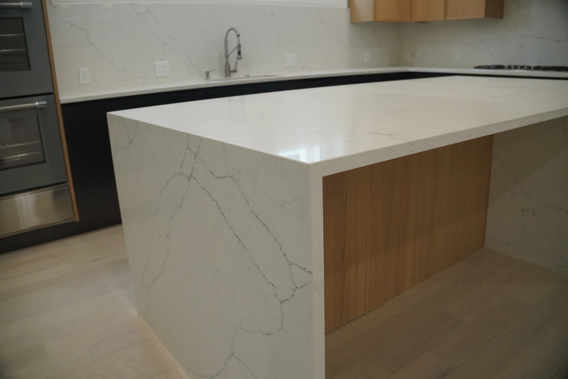 Pale veined waterfall island with a warm wood inset