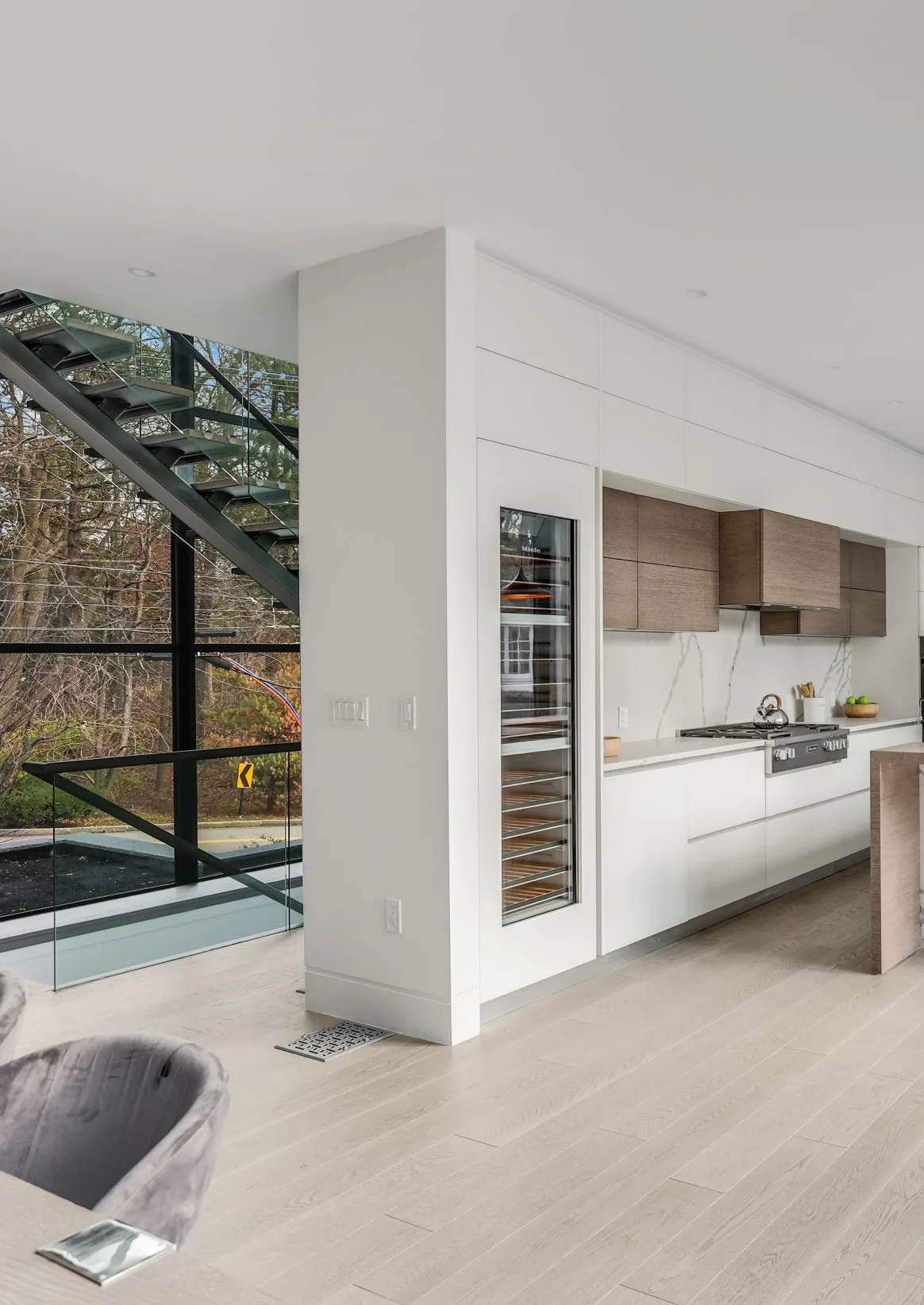 Wide kitchen view with white cabinetry and stained oak details in Wellesley