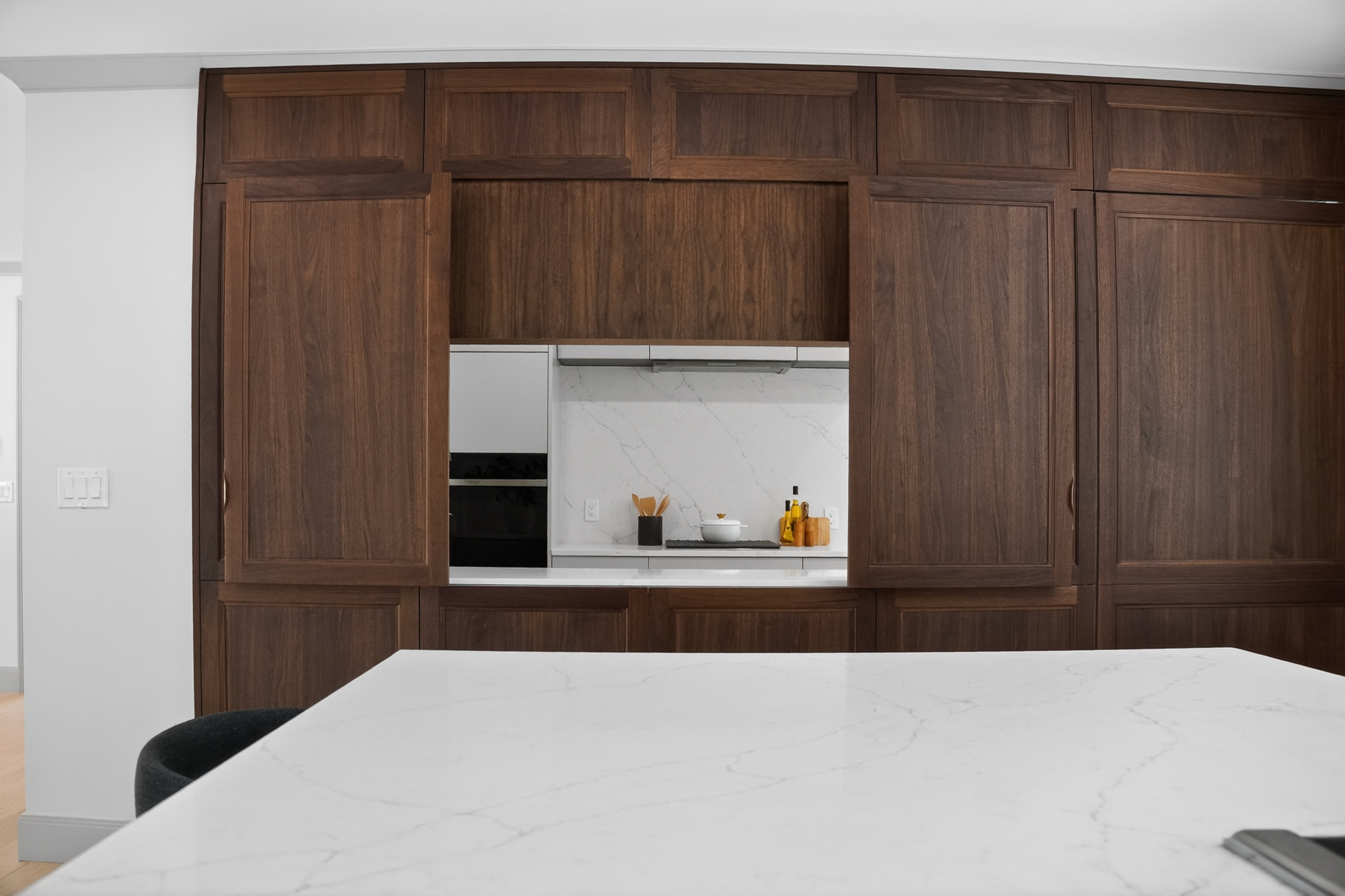 Dark wood cabinet wall behind a pale veined island in the Clinton Road kitchen