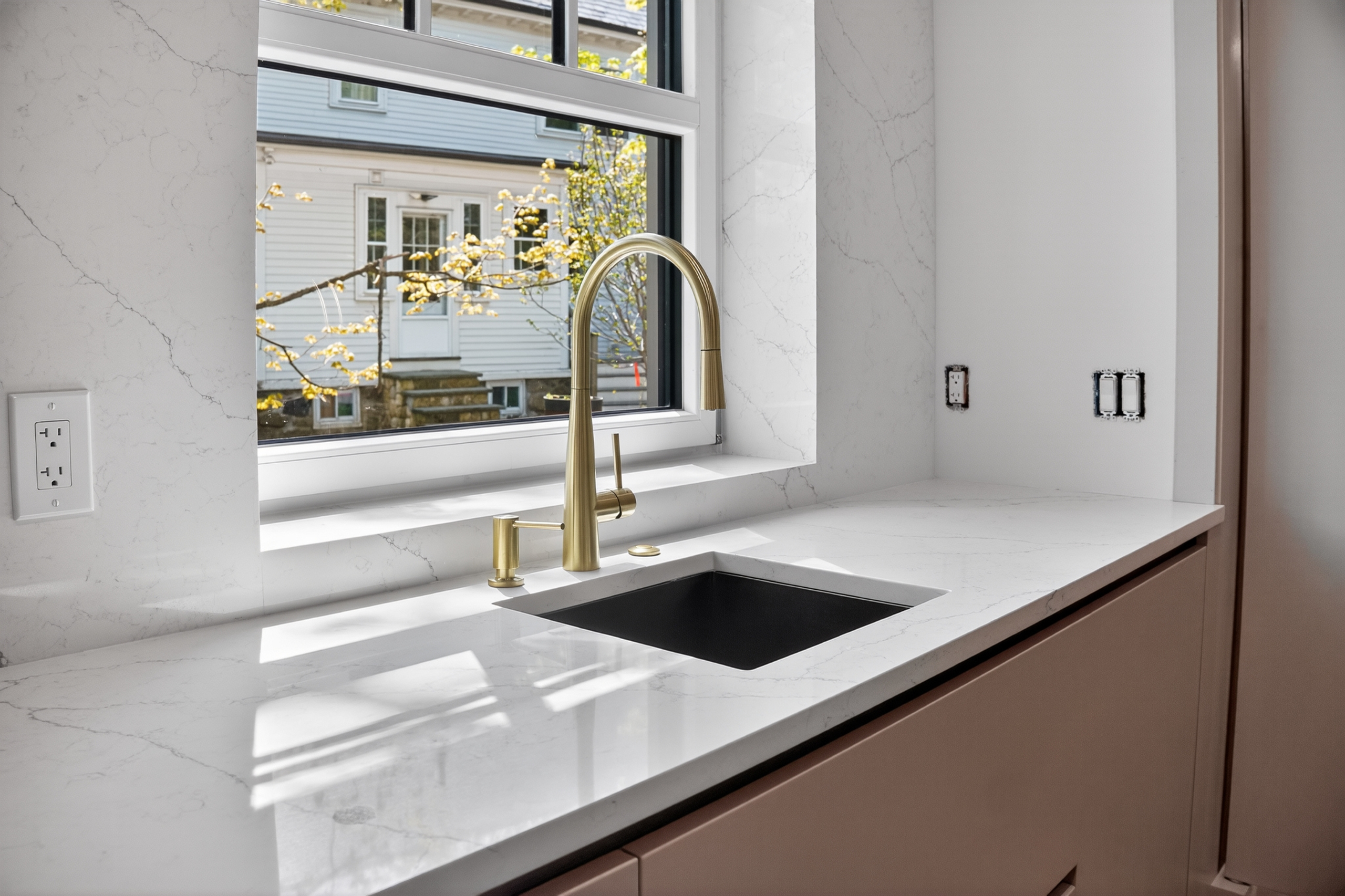 Pale veined sink surround with a gold-toned faucet in the Clinton Road kitchen