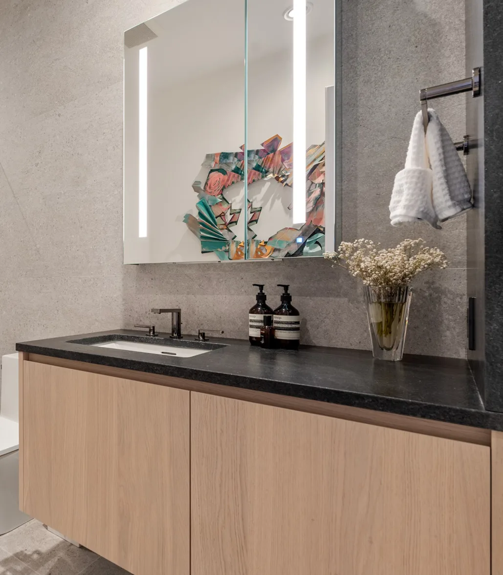 Pale oak vanity with dark counter and mirrored cabinet in the Curated Canvas Boston interior