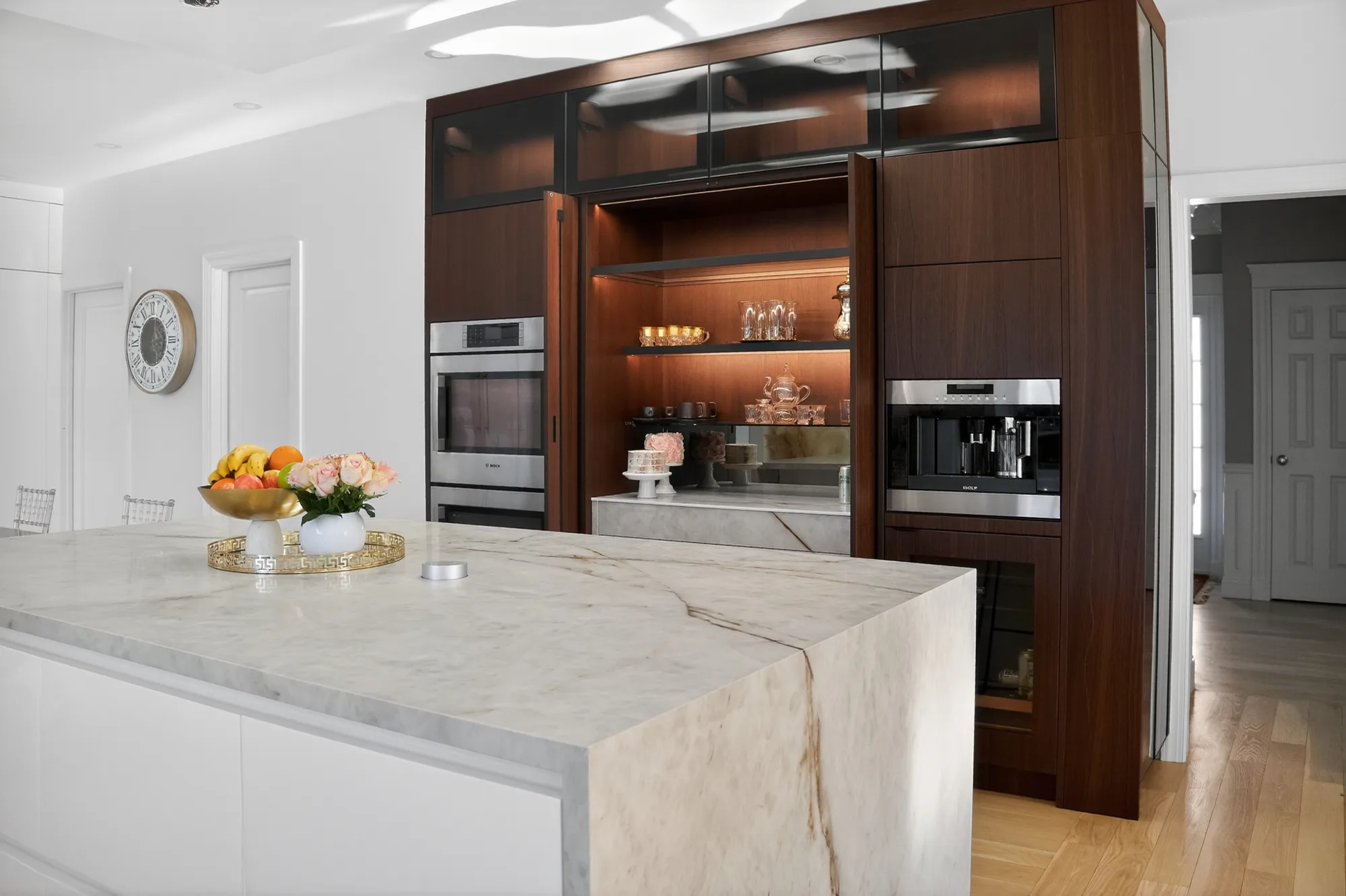 Light kitchen island facing a dark wood storage wall on Waterville Lane in Shrewsbury