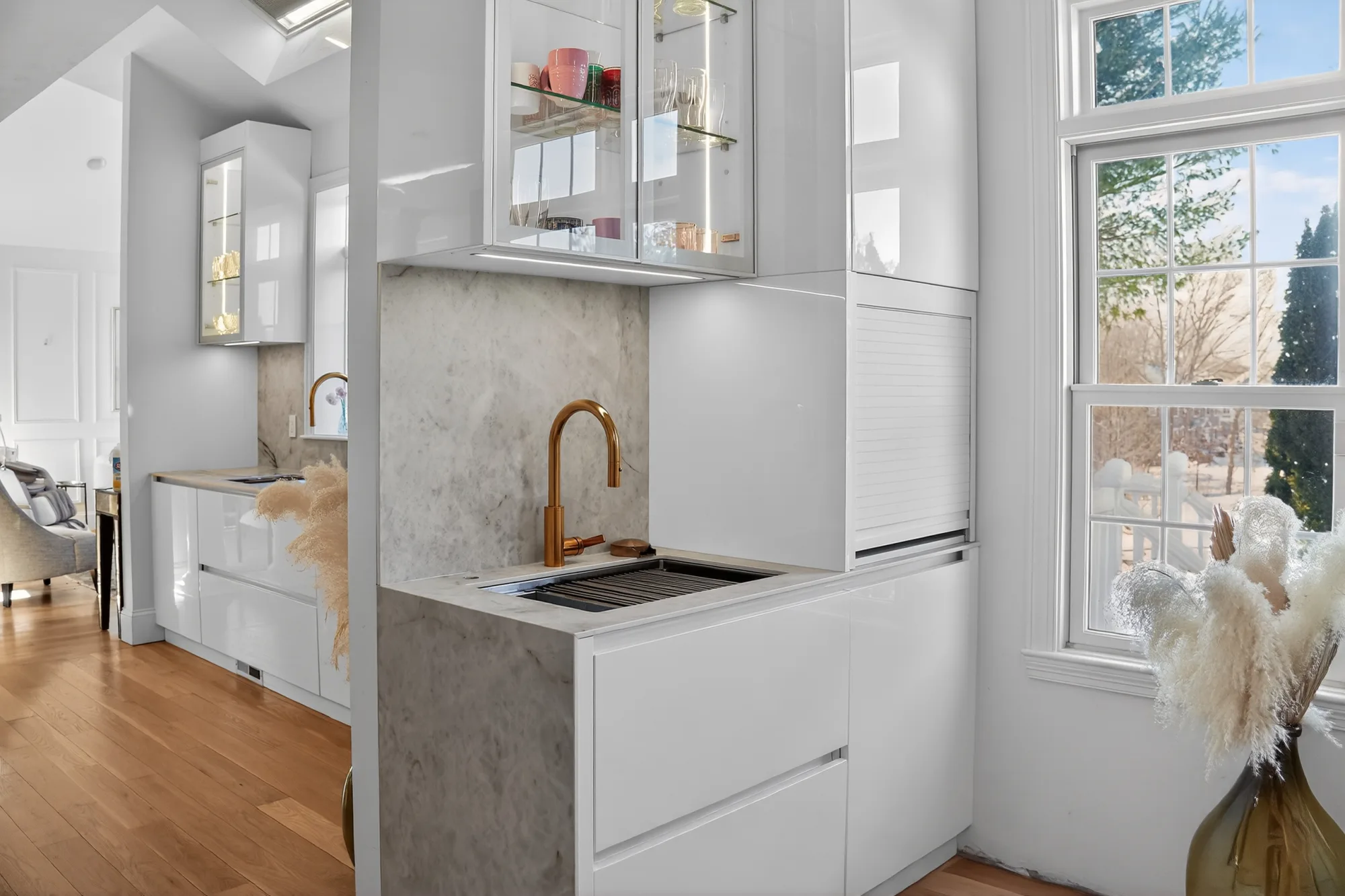 Small sink run with pale cabinetry beside a window