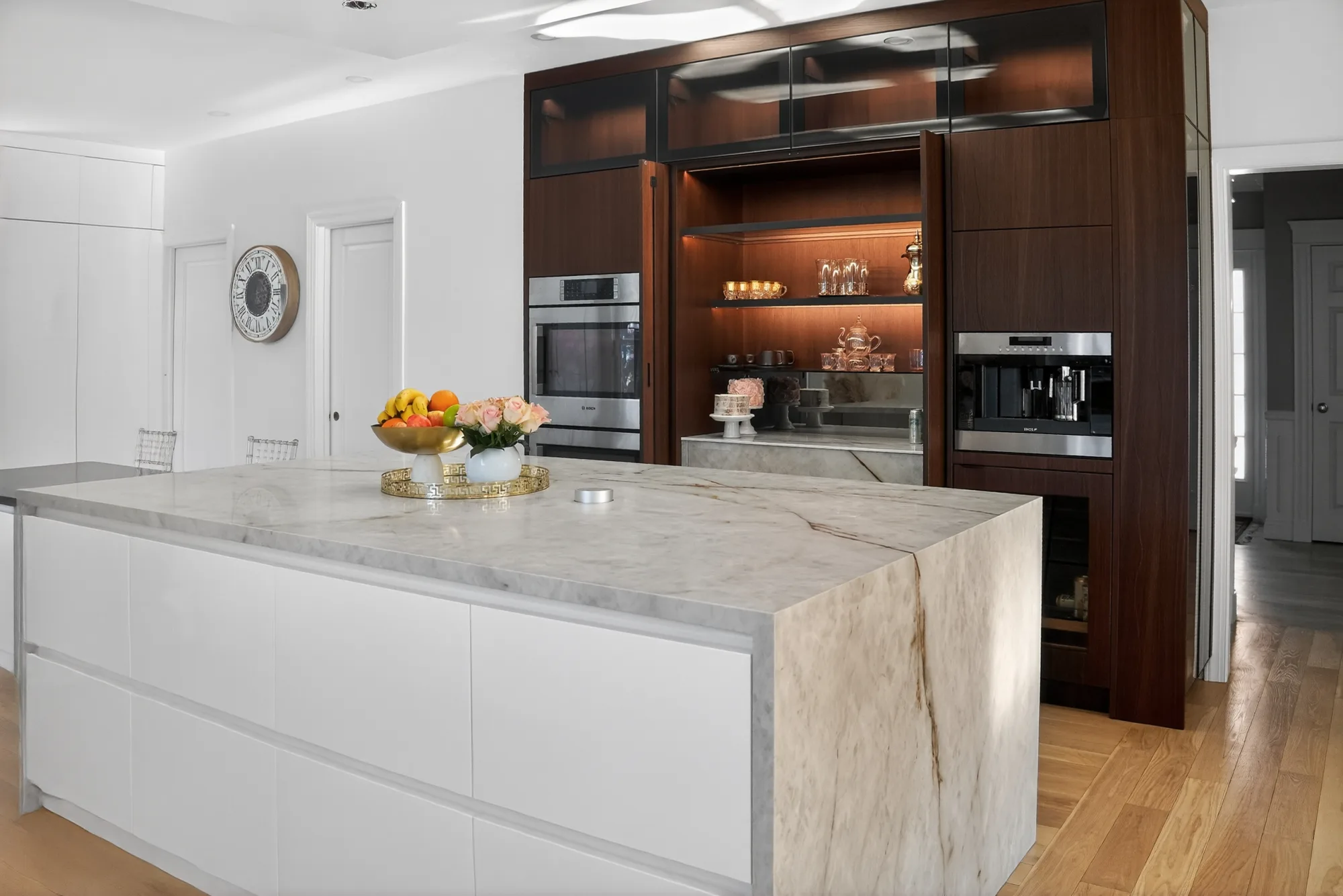 Dark wood tall storage with open shelving beyond a light island